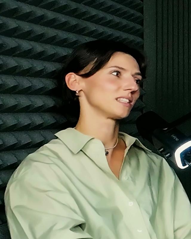 Anna Kiełbasińska w jasnozielonej koszuli mówi przy mikrofonie.
